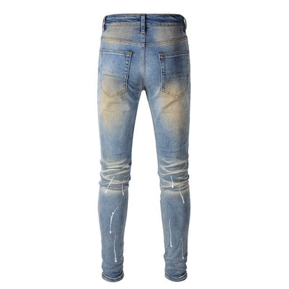 Jeans azules para hombre con parches negros, pintura desgastada y detalles rotos 523 